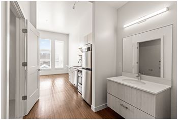 A modern kitchen with white cabinets and a wooden floor.